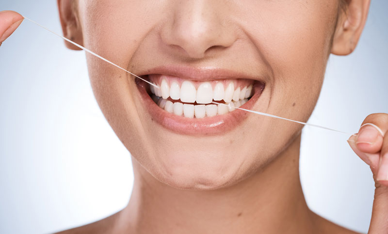 Woman, mouth and floss teeth in studio, orthodontics and cosmetics for smile on blue background