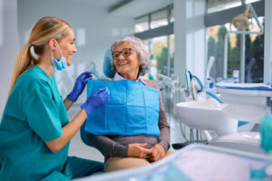 Happy elderly woman talking to her orthodontist during appointment at dentist's office. Discussing treatment process